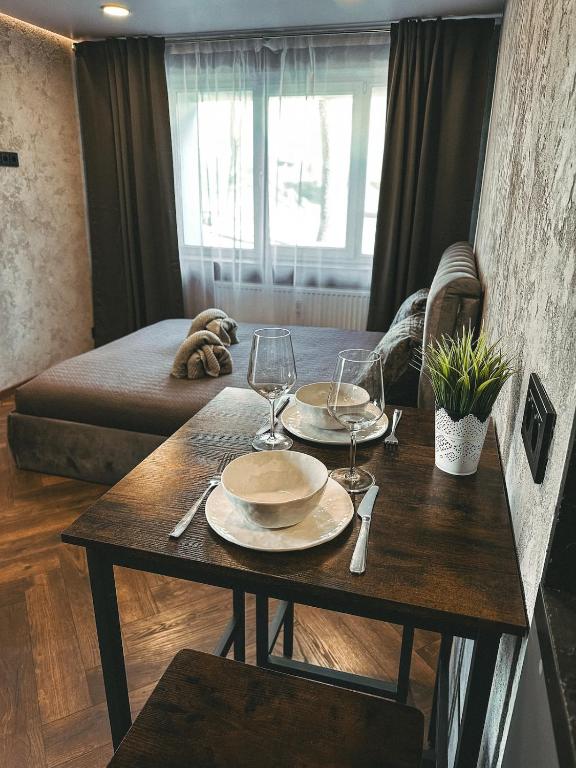 a table with two plates and wine glasses on it at Skersgatvio Apartmentai in Zarasai