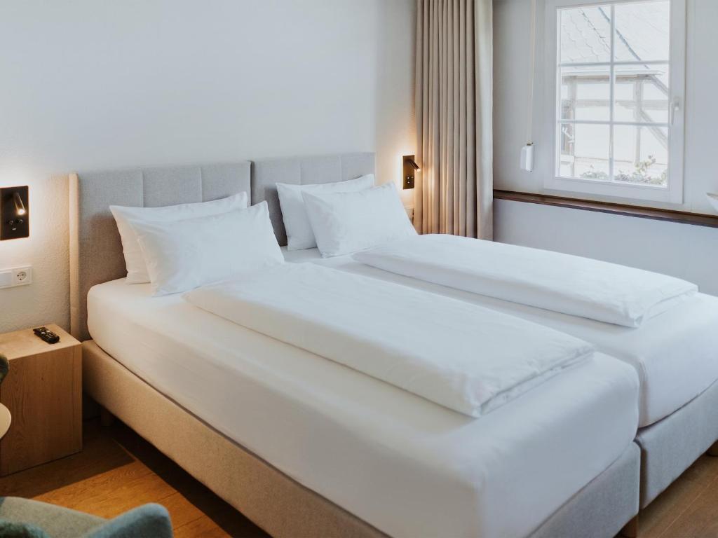 two white beds in a hotel room with a window at MYA Weinland Hotel Kobern-Gondorf in Kobern-Gondorf