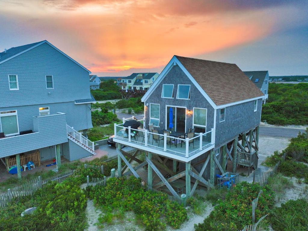 a house on a dock in front of two houses at Pet-Friendly Private Beach Oceanfront Cottage in Charlestown