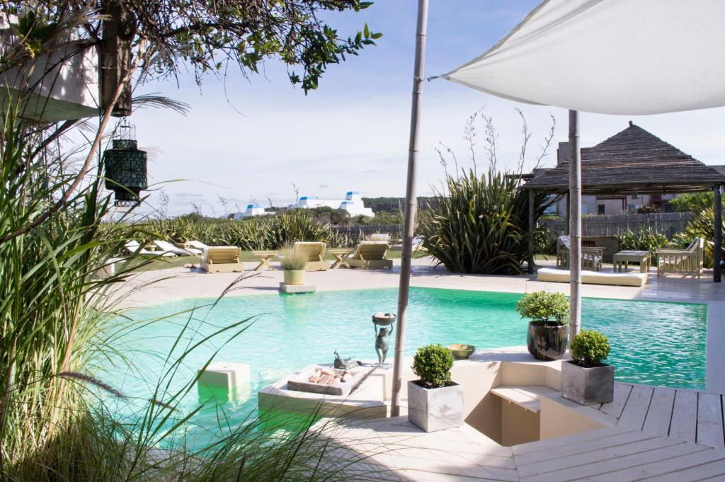 a swimming pool with chairs and an umbrella at La Posada del Faro in José Ignacio