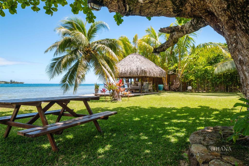 a picnic table on the grass next to the ocean at Villa Ohana - 4BR Beachfront Villa in Paopao