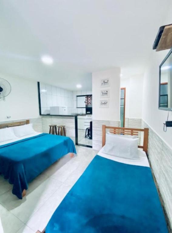 a bedroom with two beds and a kitchen at Nossa Casa Arraial LOFT in Arraial do Cabo