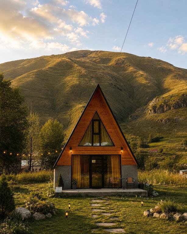 a small house with a mountain in the background at Memoria Kazbegi in Arsha