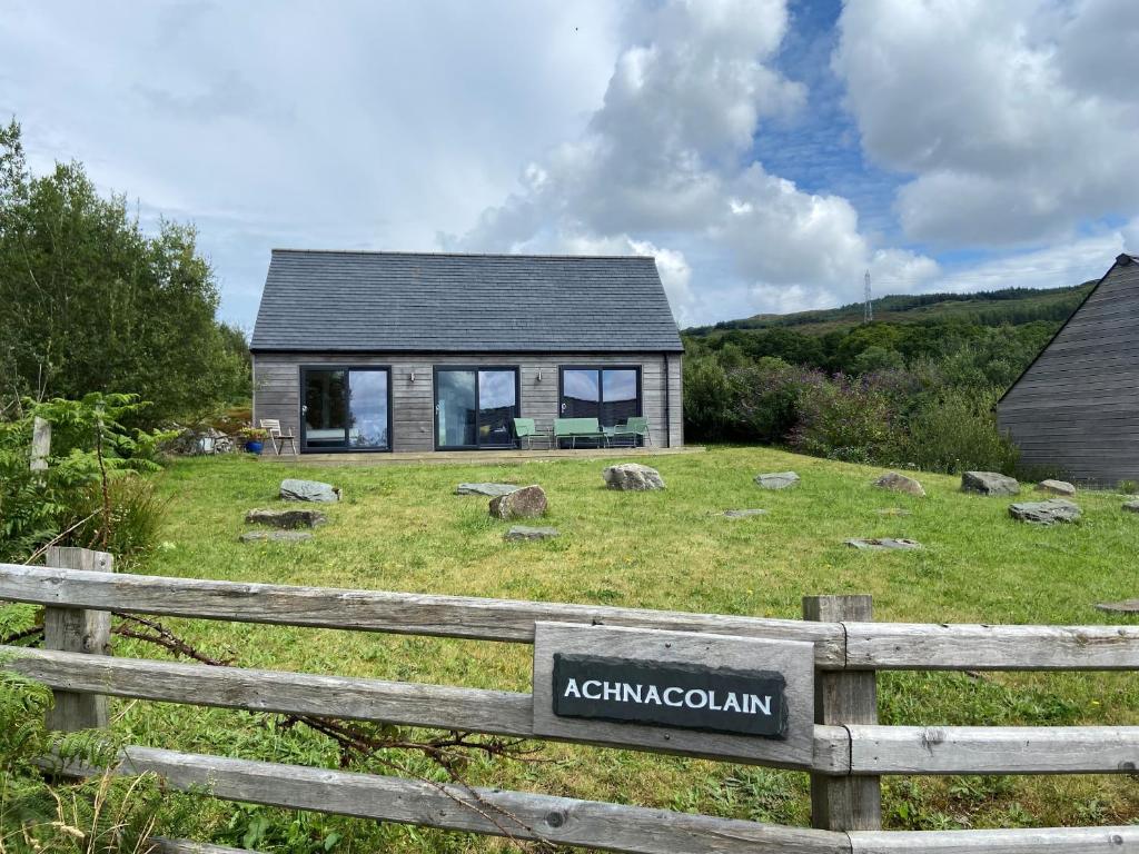 a house on a field with a fence at Achnacolain Lodge in Tarbert