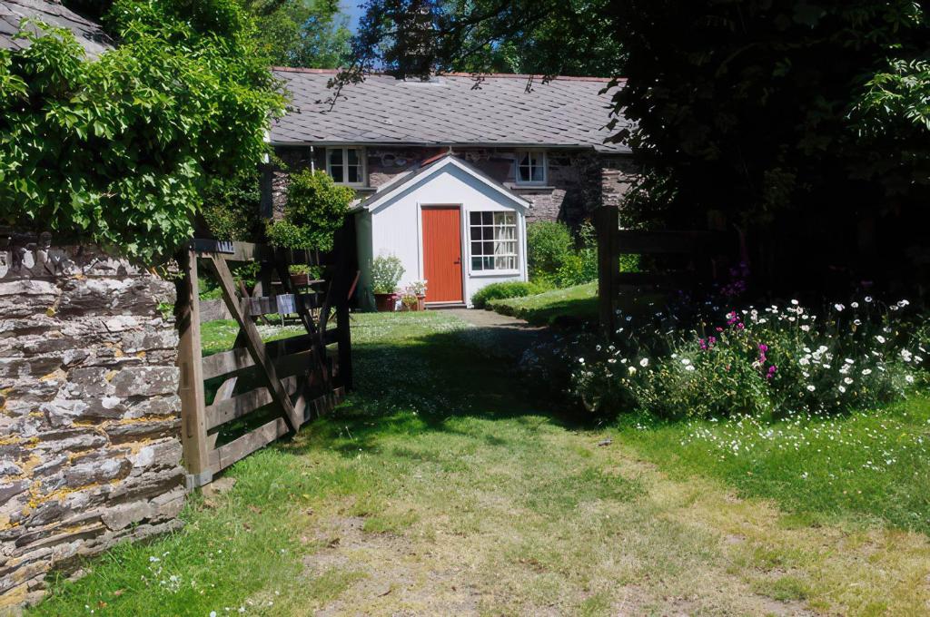 a cottage with a red door and a fence at Whitefield Cottage in Barnstaple