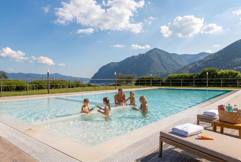 a family in a swimming pool with mountains in the background at Casa Vacanze Costa del Sole in Riva di Solto