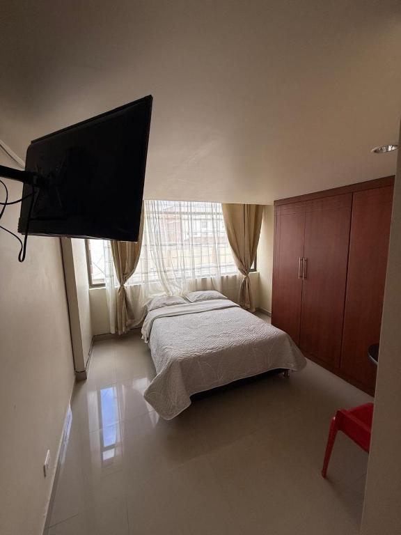 a bedroom with a bed and a flat screen tv at Hostal Brooklyn in Ipiales
