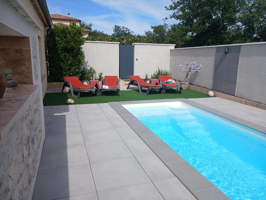 a backyard with a swimming pool and red chairs at L'Ardétente - L'Instant Présent - Villa avec piscine privée Adults Only Ardèche in Lussas