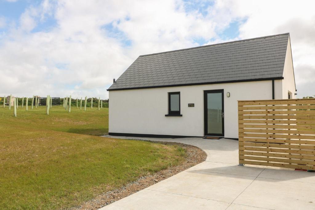a white building with a black roof and a field at Radharc an Hook Estuary Bliss in Duncannon