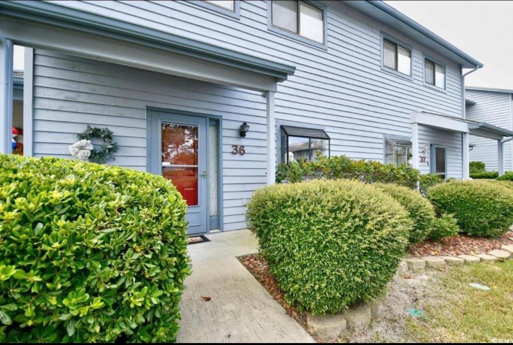 a gray house with a red door and bushes at Nice N Myrtle beach house in Little River