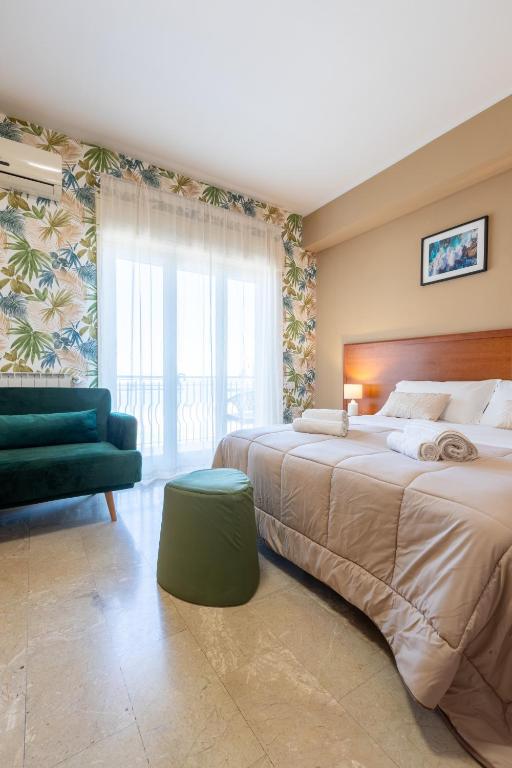 a bedroom with a large bed and a green chair at La Zagara Rooms - Porto di Milazzo in Milazzo