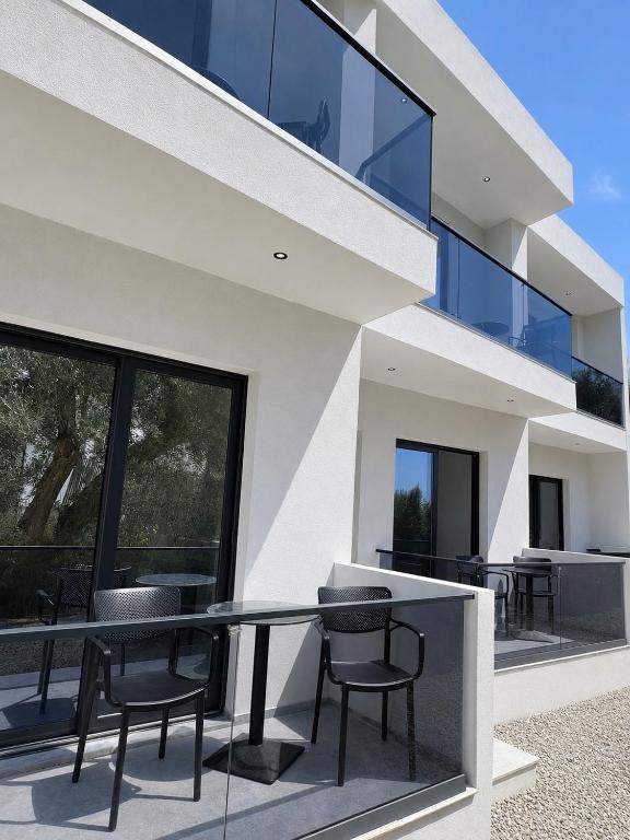 a glass house with black chairs on the balcony at Palms Guest House in Himare