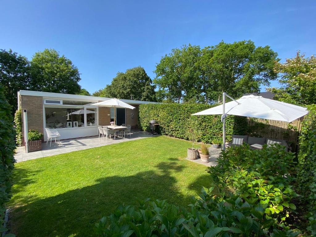 a garden with an umbrella and a patio at Holiday Home Beo in Oostkapelle