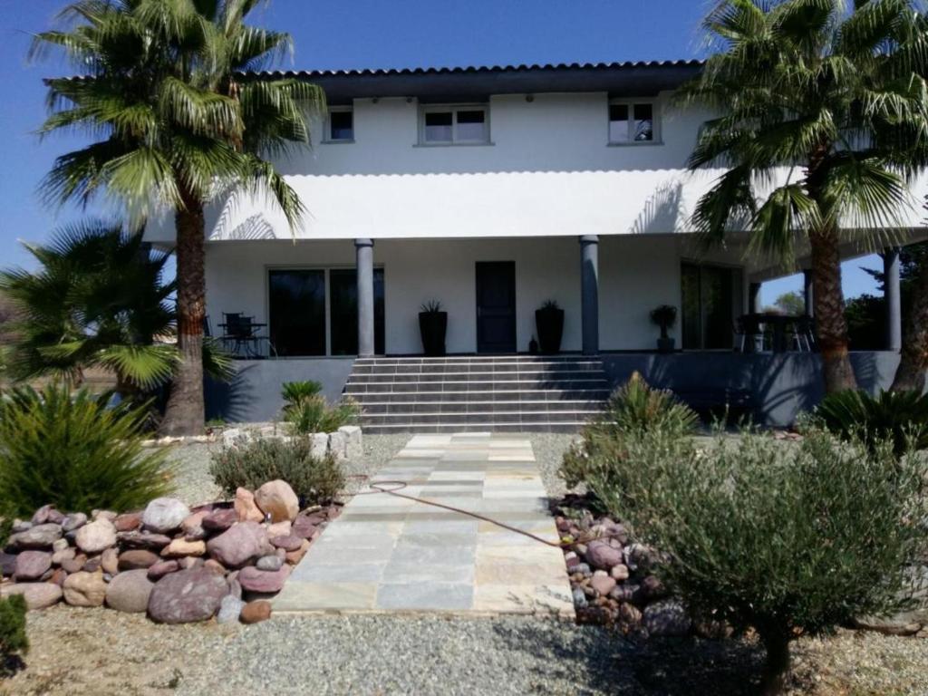 a house with palm trees in front of it at Comfortable apartment with mountain views in Ghisonaccia