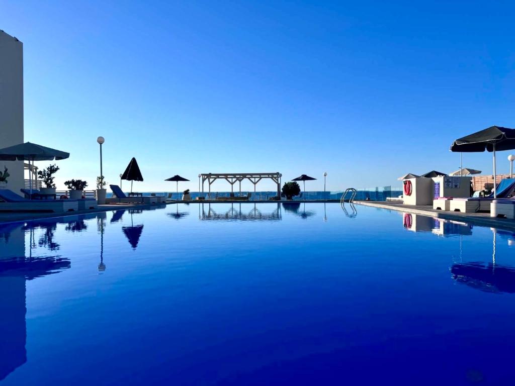 a large pool of blue water with umbrellas at Nautica Hotel Apartments in Stavromenos