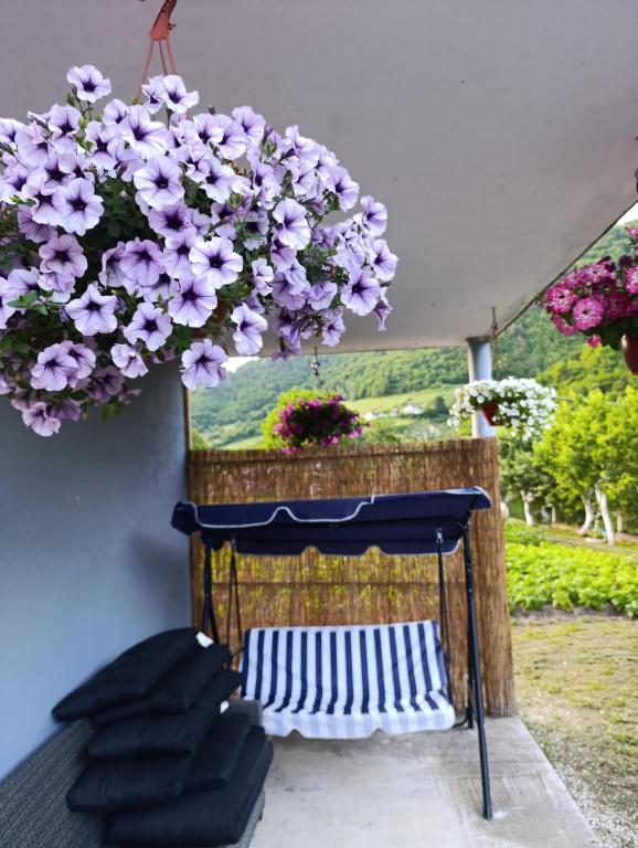 a balcony with purple flowers and a table and chairs at Apartman HUSEIN in Jajce