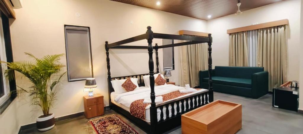 a bedroom with a black canopy bed and a green couch at Wildexoticventure in Seonī