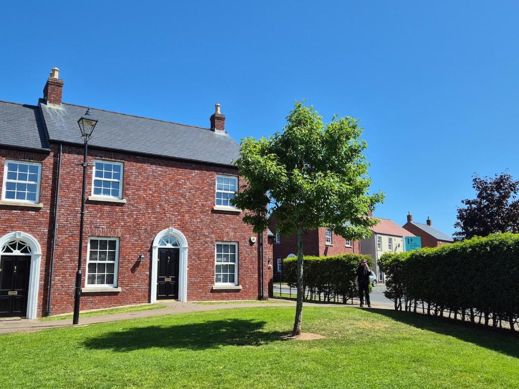 a red brick building with a tree in front of it at Charming Lisburn Flat with private parking in Lisburn
