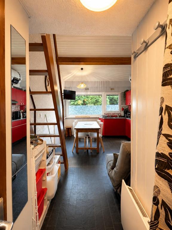 a room with a table and a kitchen with red cabinets at Cocooning Auvergnat in La Bourboule