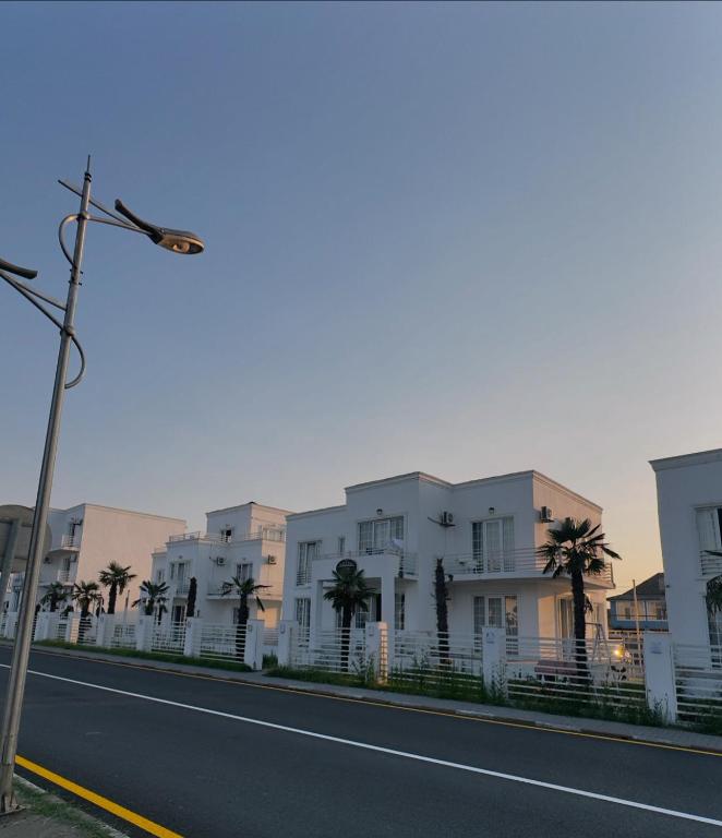 a row of white buildings with palm trees next to a street at Astara Villa Boutique Hotel in Astara