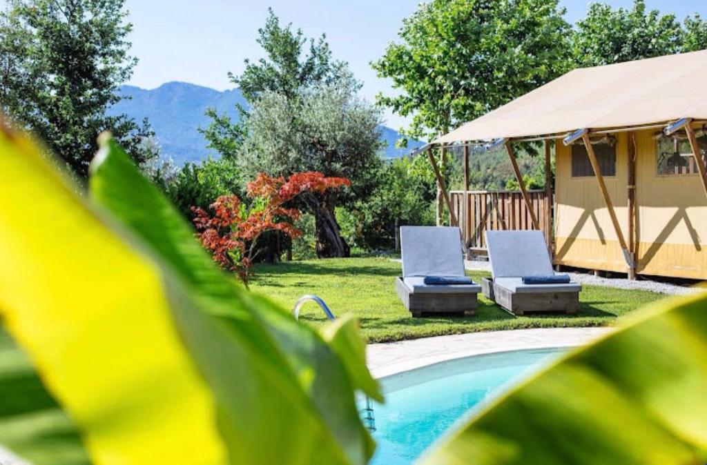 a swimming pool with two chairs and a gazebo at Glamping - Quinta do Cascalhal in Arco de Baúlhe