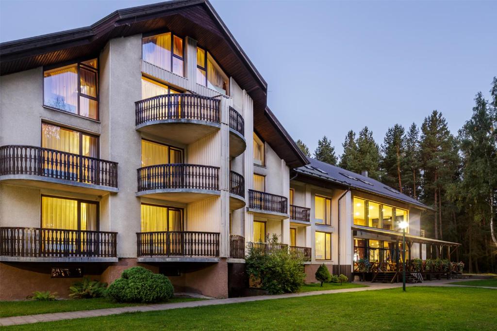 an apartment building with balconies and a lawn at Viešbutis "Linelis" in Paplatelė