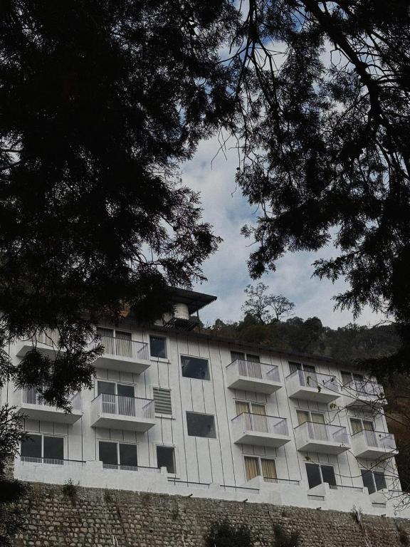 a large white building with trees in front of it at Ramasa Lake House in Bhīm Tāl