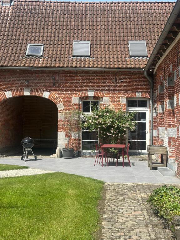 a brick building with a patio with a table and a grill at Le Sart de Bouland in Frasnes-lez-Anvaing