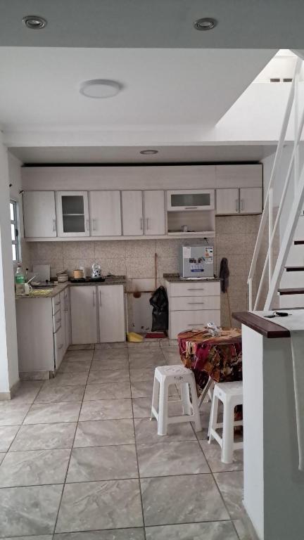 a kitchen with white cabinets and a table and chairs at Casa céntrica de 2 dormitorios in Cañada de Gómez