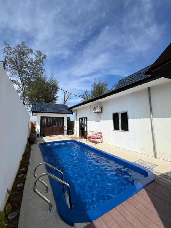 a blue swimming pool in front of a house at Tamu Beradu Seaview Private Pool Villa in Dungun