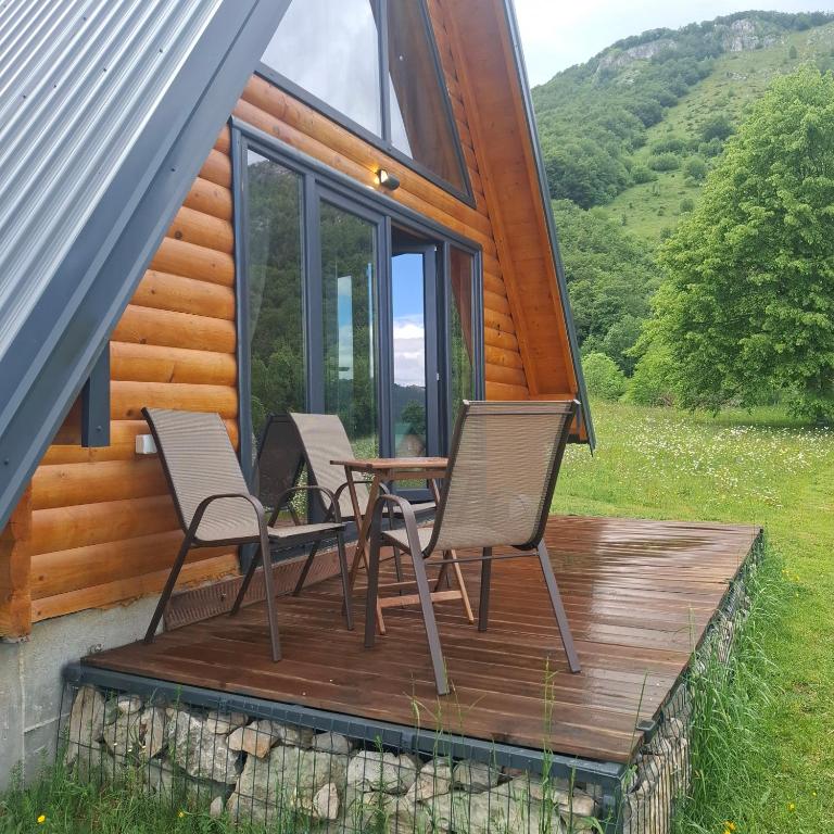 a deck with two chairs and a table on a cabin at Korijeni in Šavnik
