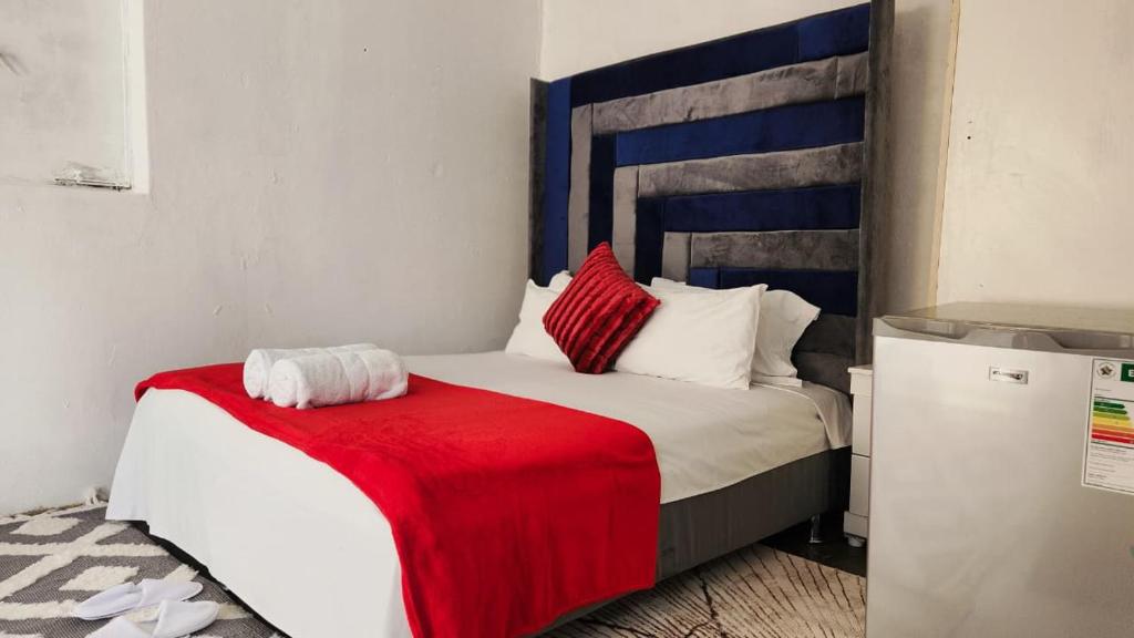 a bedroom with a bed with a red blanket on it at Olympia GuestHouse in Kempton Park