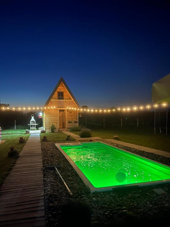 a green pool in front of a barn at night at Kućica naša bajka in Kupinovo