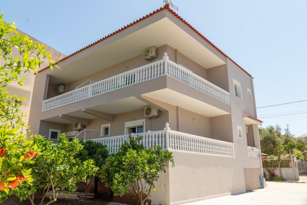 a house with white balconies and trees at Joy & Grace Apartments Ksamil in Ksamil