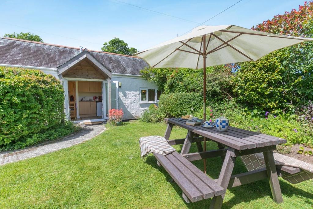 a wooden picnic table with an umbrella and a bench at 1 Bed in Falmouth oc-85594 in Constantine