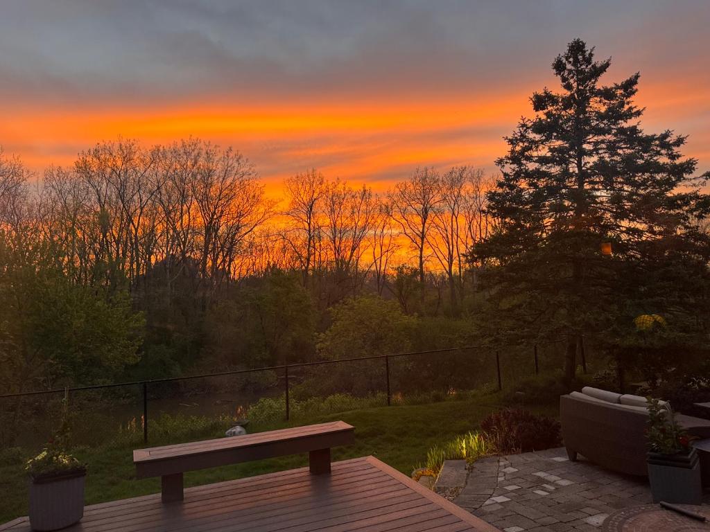 a bench on a deck with a sunset in the background at Quiet Cozy Luxury on the Thames in Ontario! in London