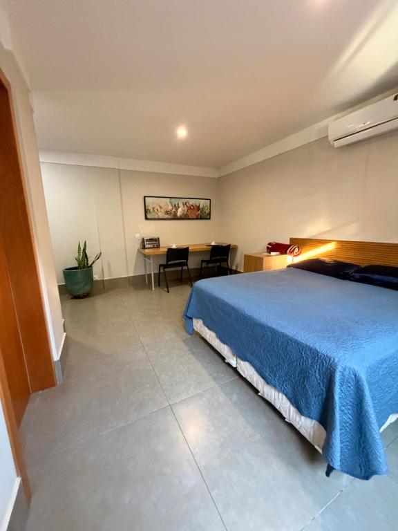 a bedroom with a blue bed and a table at Studio Central IV in Cascavel