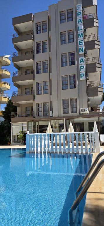 a hotel with a swimming pool in front of a building at Palmen Apart Hotel in Alanya