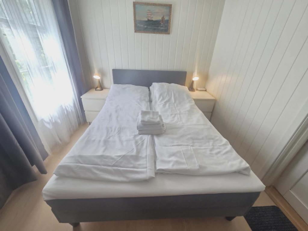 a bed with white sheets and two lights on the sides at Stavangerliving in Stavanger