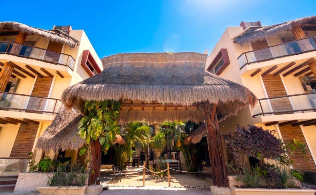 a straw hut in front of a building at Jardín del Mar by ÓOL Hotels in Holbox Island