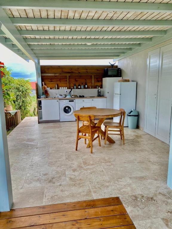 a kitchen with a wooden table and a table and chairs at Charmant Bungalow Independant in Grand-Bourg