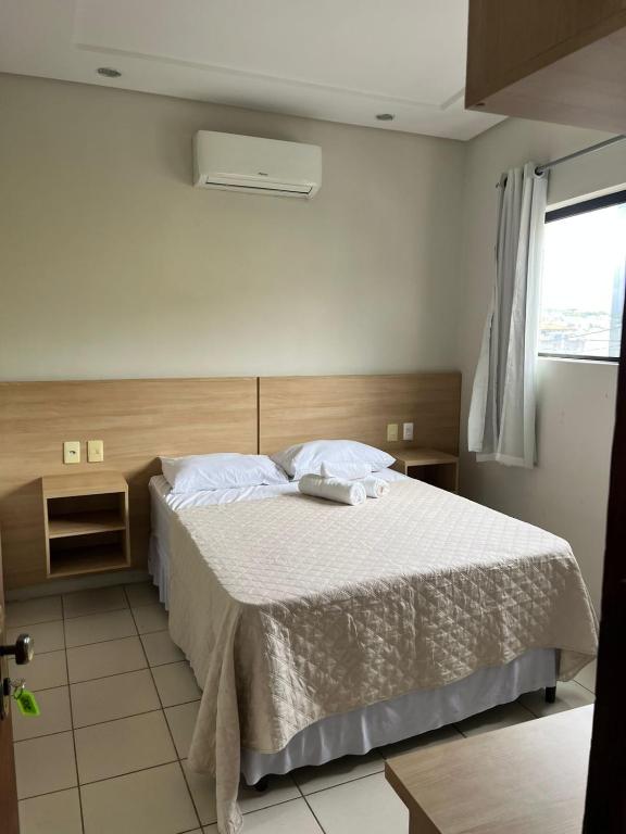 a bedroom with a bed with white sheets and a window at Hotel Piracema in Caruaru