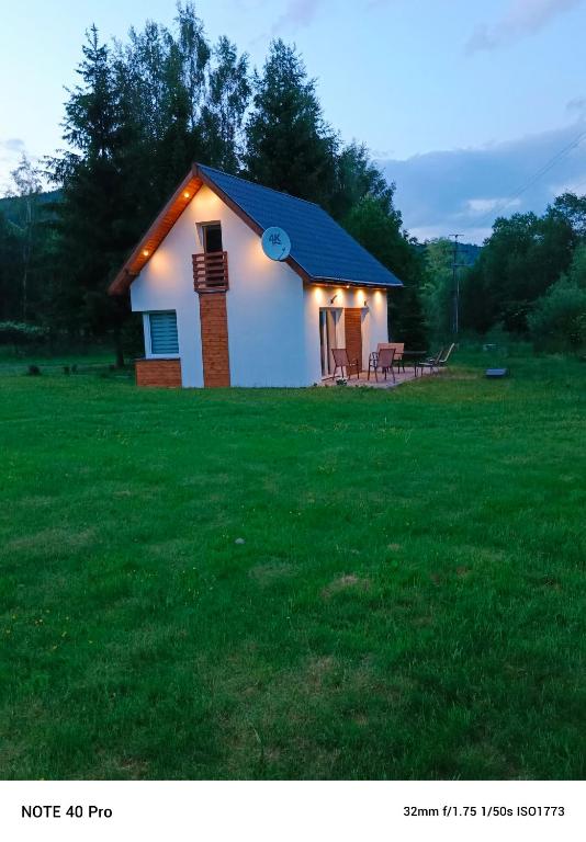 a small house with lights on it in a field at Leszczynka in Szarocin