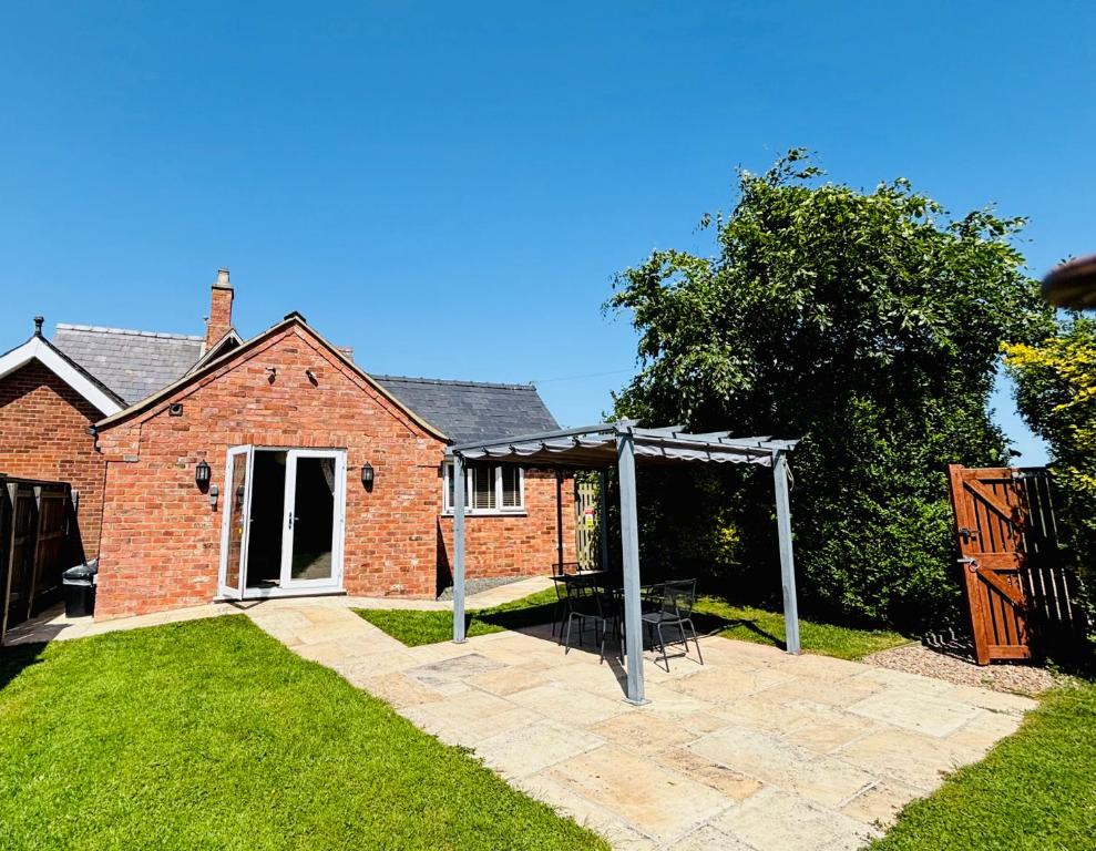 a brick house with a pergola in the yard at The Old Gate House Annexe in Alford