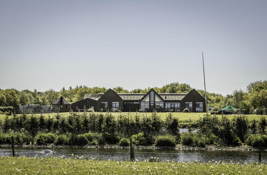 a row of houses in a field next to a river at Fantastic Holiday Property Kragelund For Up To 24 Guests! in Åbybro