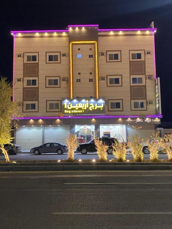 a large building with cars parked in front of it at شقق برج أربعين واحد in Al Qurayyat