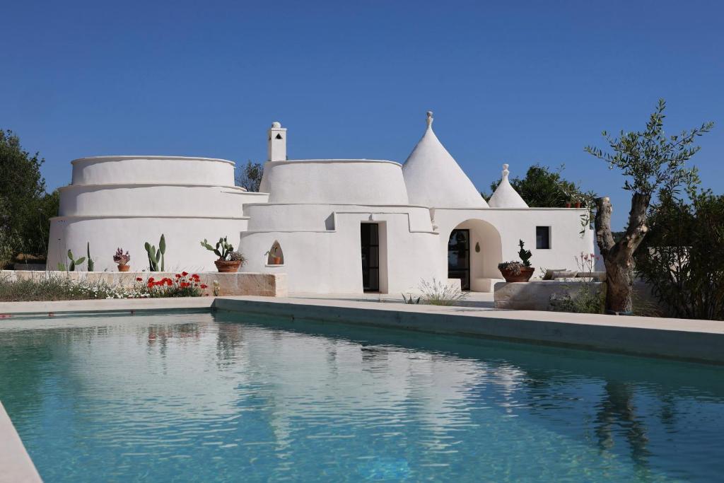 a white house with a swimming pool in front of it at Trulli Lumena in Ostuni