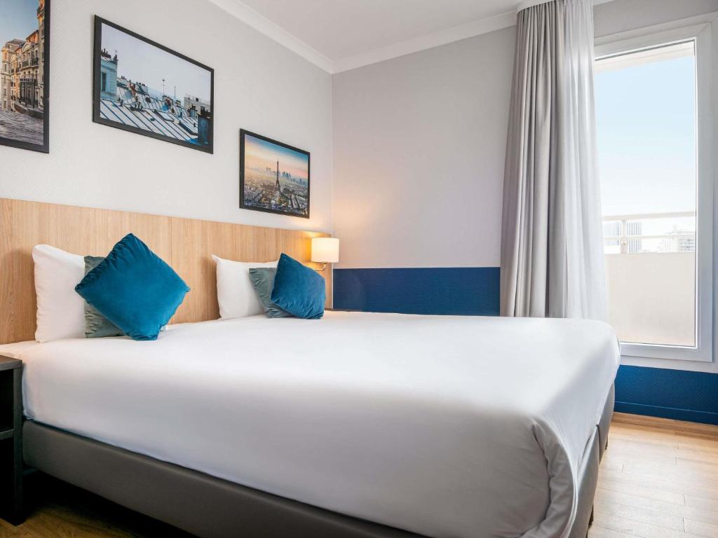 a large bed in a hotel room with blue accents at Aparthotel Adagio La Défense Kléber in Courbevoie
