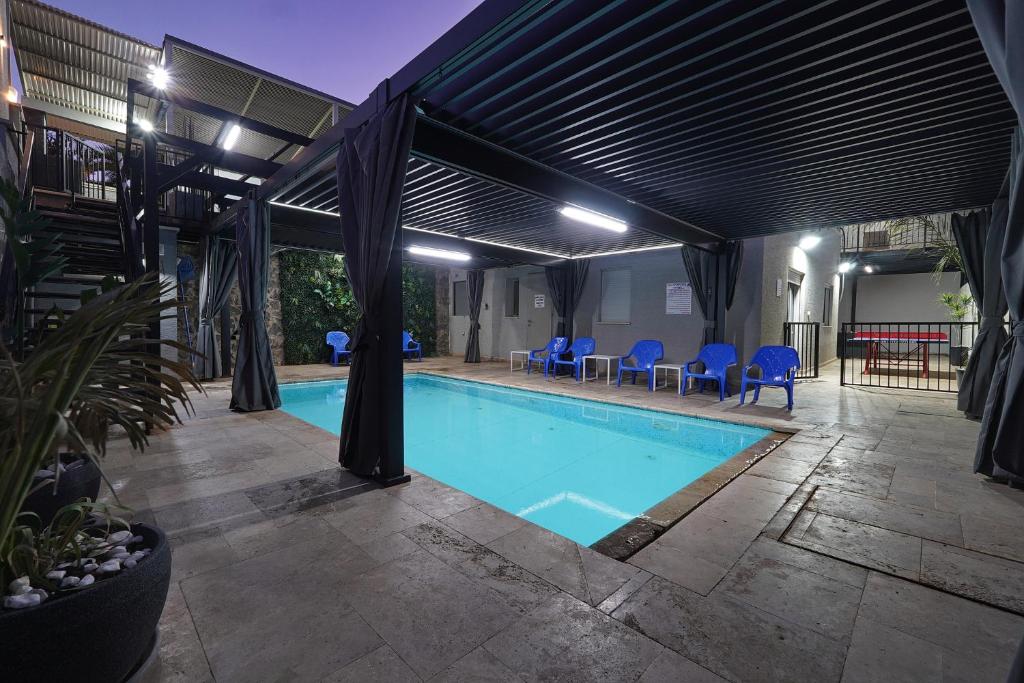 a swimming pool with a pergola and blue chairs at וילה מארי עם בריכה במגדל in Migdal