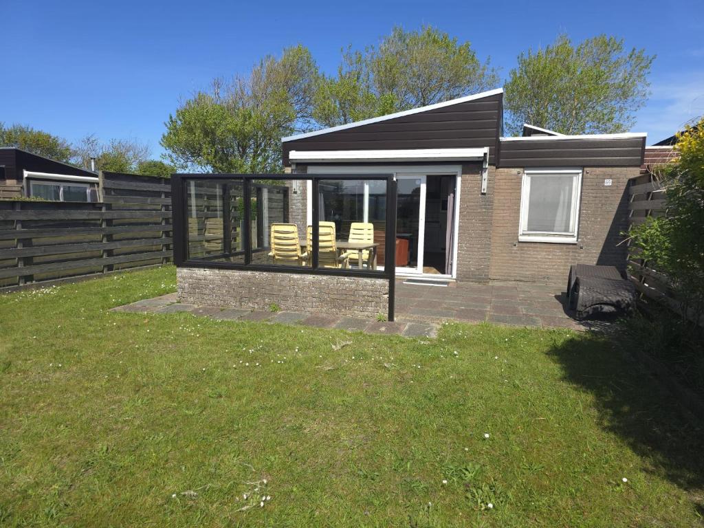 a small house with a patio and chairs in a yard at De Blenck 69 in Callantsoog
